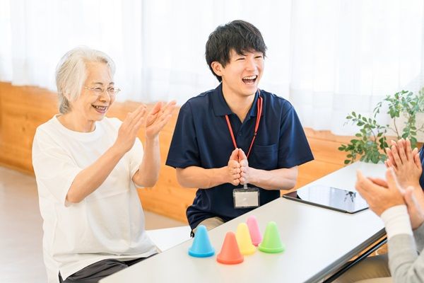 テーブルを囲んでレクリエーションをする高齢の方と職員
