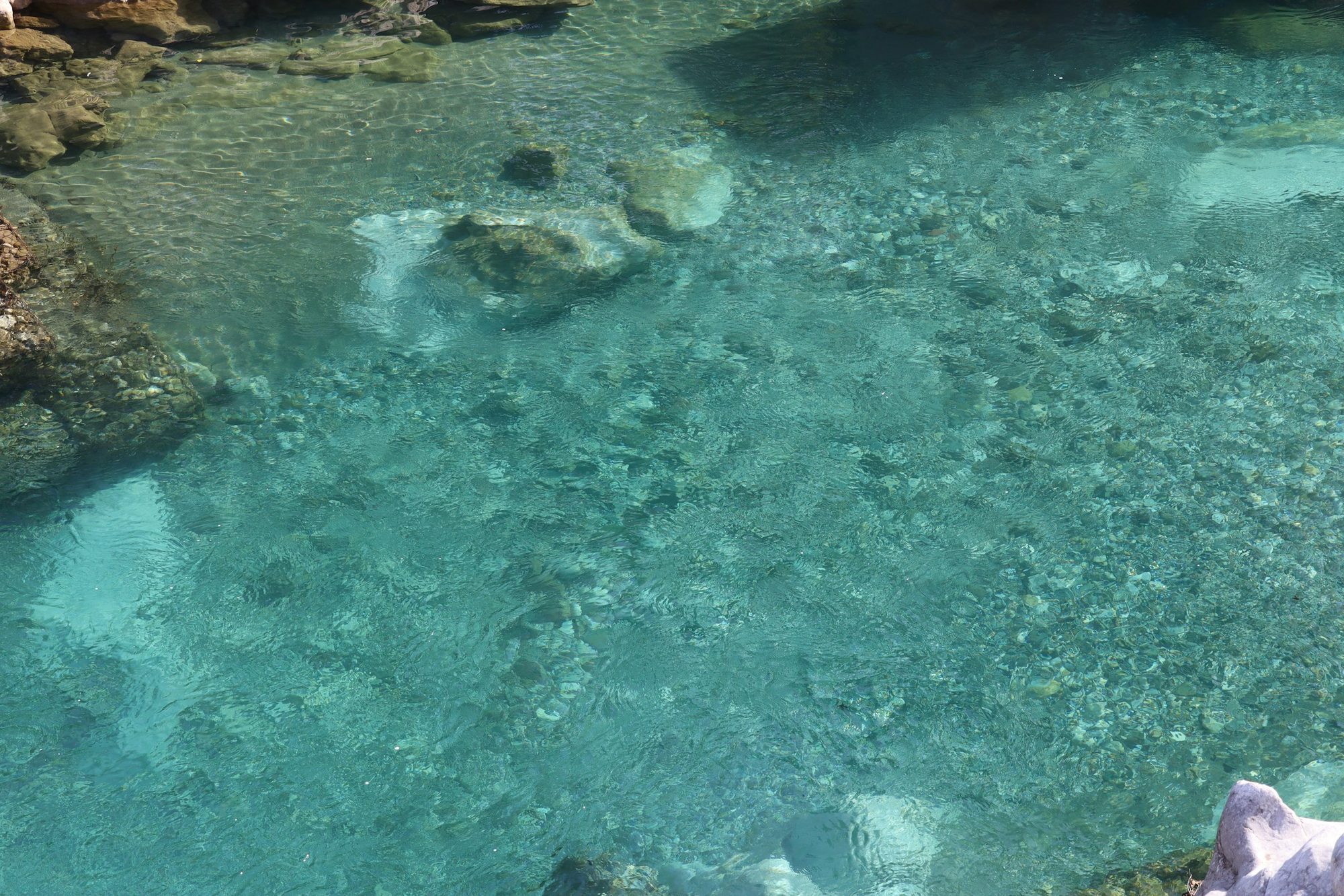 岩の間をゆるやかに流れる、澄んだ青緑の水