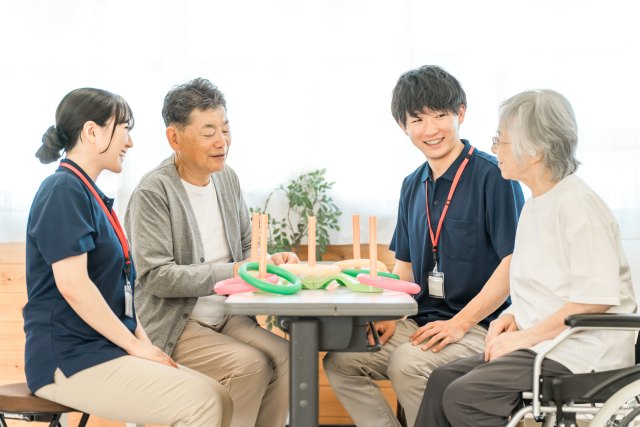 輪投げを囲んで笑う高齢の男性と女性、職員たち